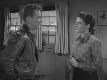 Movie still from “The Thing from Another World” (1951), directed by Howard Hawks – A man and a woman standing next to each other in front of a window; Medium shot, Over the shoulder angle