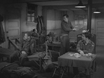 Movie still from “The Thing from Another World” (1951), directed by Howard Hawks – A black and white photo of a group of men sitting around a table; Wide shot, High angle