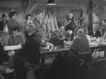 Movie still from “The Thing from Another World” (1951), directed by Howard Hawks – A group of people sitting around a table; Wide shot, High angle