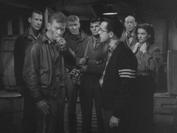 Movie still from “The Thing from Another World” (1951), directed by Howard Hawks – A group of men standing around each other in front of a building; Medium shot, High angle