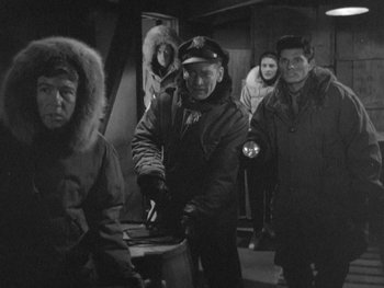 Movie still from “The Thing from Another World” (1951), directed by Howard Hawks – A black and white photo of a group of people in a room; Medium shot, High angle