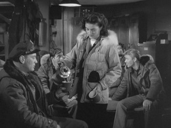 Movie still from “The Thing from Another World” (1951), directed by Howard Hawks – An old photo of a group of men and a woman; Medium shot, High angle