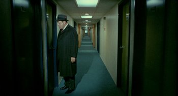 Movie still from “The Thomas Crown Affair” (1968), directed by Norman Jewison – A man in a black coat and a black hat standing in a hallway; Wide shot, High angle