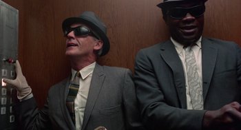 Movie still from “The Thomas Crown Affair” (1968), directed by Norman Jewison – A man in a suit and tie next to another man in a suit and tie; Medium shot, Low angle