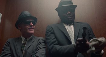 Movie still from “The Thomas Crown Affair” (1968), directed by Norman Jewison – Two men in suits and hats are sitting in a room; Medium shot, Low angle