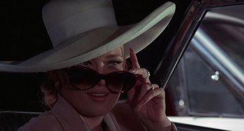 Movie still from “The Thomas Crown Affair” (1968), directed by Norman Jewison – A woman wearing a white hat and sunglasses in a car; Close Up shot, Low angle