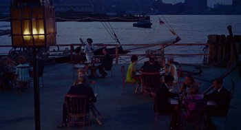 Movie still from “The Thomas Crown Affair” (1968), directed by Norman Jewison – A group of people sitting at tables on a boat; Extreme Wide shot, High angle