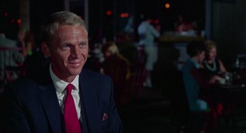 Movie still from “The Thomas Crown Affair” (1968), directed by Norman Jewison – A man in a suit and tie standing in a restaurant; Medium shot, Over the shoulder angle