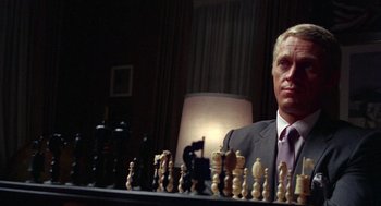 Movie still from “The Thomas Crown Affair” (1968), directed by Norman Jewison – A man in a suit and tie sitting in front of chess pieces; Close Up shot, Over the shoulder angle