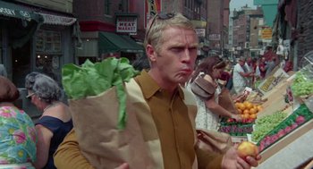 Movie still from “The Thomas Crown Affair” (1968), directed by Norman Jewison – A man holding a bag of lettuce in a market; Medium shot, Over the shoulder angle