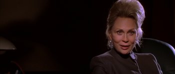 Movie still from “The Thomas Crown Affair” (1999), directed by John McTiernan – An older woman wearing a black shirt and a pair of silver earrings; Close Up shot, Over the shoulder angle