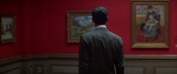 Movie still from “The Thomas Crown Affair” (1999), directed by John McTiernan – A man standing in front of a painting in a room; Medium shot, Over the shoulder angle