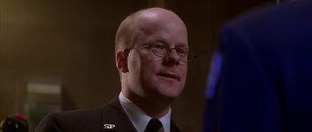 Movie still from “The Thomas Crown Affair” (1999), directed by John McTiernan – A man with a bald head wearing glasses and a tie; Close Up shot, Low angle