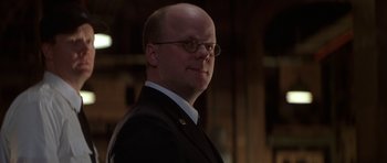 Movie still from “The Thomas Crown Affair” (1999), directed by John McTiernan – A man in a suit and glasses is looking at the camera; Close Up shot, Low angle