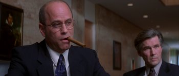 Movie still from “The Thomas Crown Affair” (1999), directed by John McTiernan – A man in a suit and tie holding a cigar in his mouth; Close Up shot, Low angle