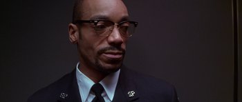 Movie still from “The Thomas Crown Affair” (1999), directed by John McTiernan – A person wearing a suit and glasses; Close Up shot, Low angle