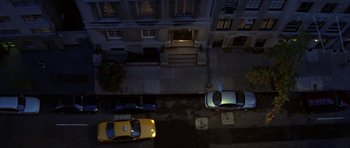 Movie still from “The Thomas Crown Affair” (1999), directed by John McTiernan – Cars are parked on the side of the street at night; Extreme Wide shot, Overhead angle