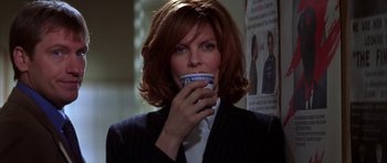 Movie still from “The Thomas Crown Affair” (1999), directed by John McTiernan – A woman with red hair is drinking a cup of coffee; Close Up shot, Low angle
