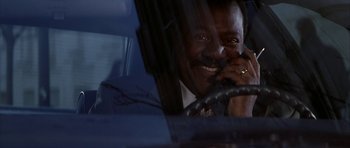 Movie still from “The Thomas Crown Affair” (1999), directed by John McTiernan – A man sitting in the driver's seat of a car talking on the phone; Close Up shot, Low angle