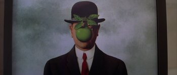 Movie still from “The Thomas Crown Affair” (1999), directed by John McTiernan – A man in a suit and hat with an apple on his face; Close Up shot, Overhead angle