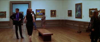 Movie still from “The Thomas Crown Affair” (1999), directed by John McTiernan – A group of people standing in a room with paintings on the wall; Medium shot, Over the shoulder angle