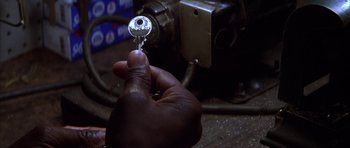 Movie still from “The Thomas Crown Affair” (1999), directed by John McTiernan – A hand holding a key to a key hole; Extreme Close Up shot, High angle