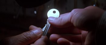 Movie still from “The Thomas Crown Affair” (1999), directed by John McTiernan – A person holding a key in their hand; Extreme Close Up shot, Overhead angle