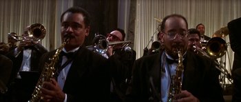 Movie still from “The Thomas Crown Affair” (1999), directed by John McTiernan – A group of men in tuxedos playing musical instruments; Medium shot, Low angle
