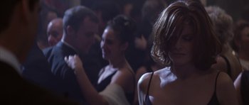 Movie still from “The Thomas Crown Affair” (1999), directed by John McTiernan – A group of people sitting in a dark room; Close Up shot, Over the shoulder angle