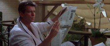 Movie still from “The Thomas Crown Affair” (1999), directed by John McTiernan – A man sitting on a chair reading a newspaper; Close Up shot, Low angle