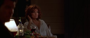 Movie still from “The Thomas Crown Affair” (1999), directed by John McTiernan – A woman sitting at a table with a glass of red wine; Medium shot, Low angle