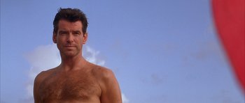 Movie still from “The Thomas Crown Affair” (1999), directed by John McTiernan – A man with no shirt is posing for a picture; Close Up shot, Low angle
