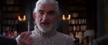 Movie still from “The Thomas Crown Affair” (1999), directed by John McTiernan – An older man in a sweater is talking to the camera; Close Up shot, High angle