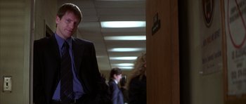Movie still from “The Thomas Crown Affair” (1999), directed by John McTiernan – A man in a suit and tie in a hallway; Medium shot, Over the shoulder angle