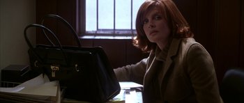Movie still from “The Thomas Crown Affair” (1999), directed by John McTiernan – A woman sitting at a table with a purse in front of her; Medium shot, Low angle