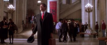 Movie still from “The Thomas Crown Affair” (1999), directed by John McTiernan – A man in a suit and red tie holding a briefcase; Wide shot, Low angle