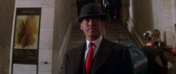 Movie still from “The Thomas Crown Affair” (1999), directed by John McTiernan – A man in a suit and tie standing in front of a staircase; Close Up shot, Low angle