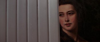 Movie still from “The Thomas Crown Affair” (1999), directed by John McTiernan – A young woman peeking out from behind a metal fence; Close Up shot, Over the shoulder angle