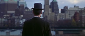 Movie still from “The Thomas Crown Affair” (1999), directed by John McTiernan – A man wearing a black suit and a black hat; Close Up shot, Over the shoulder angle