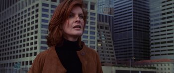 Movie still from “The Thomas Crown Affair” (1999), directed by John McTiernan – A person wearing a jacket near a building; Close Up shot, Low angle