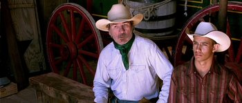 Movie still from “The Three Burials of Melquiades Estrada” (2005), directed by Tommy Lee Jones – A man wearing a cowboy hat sitting in front of a wagon; Close Up shot, Over the shoulder angle