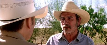 Movie still from “The Three Burials of Melquiades Estrada” (2005), directed by Tommy Lee Jones – A man wearing a cowboy hat talking to another man; Close Up shot, Over the shoulder angle