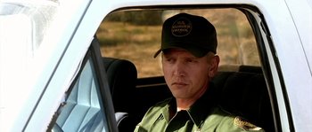 Movie still from “The Three Burials of Melquiades Estrada” (2005), directed by Tommy Lee Jones – A man wearing a hat sitting in the driver's seat of a car; Close Up shot, Over the shoulder angle