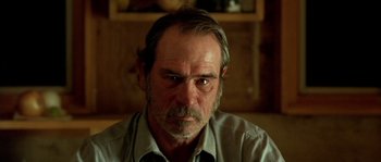 Movie still from “The Three Burials of Melquiades Estrada” (2005), directed by Tommy Lee Jones – An older man with a beard and mustache looking at the camera; Close Up shot, Over the shoulder angle