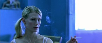 Movie still from “The Three Burials of Melquiades Estrada” (2005), directed by Tommy Lee Jones – A beautiful young lady sitting in front of a blue wall; Close Up shot, Over the shoulder angle