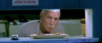 Movie still from “The Three Burials of Melquiades Estrada” (2005), directed by Tommy Lee Jones – An older man wearing an apron looking at a plate of food; Close Up shot, Low angle