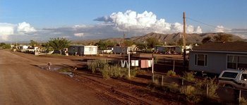 Movie still from “The Three Burials of Melquiades Estrada” (2005), directed by Tommy Lee Jones – A dirt field with a lot of buildings in the background; Extreme Wide shot, Low angle
