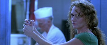 Movie still from “The Three Burials of Melquiades Estrada” (2005), directed by Tommy Lee Jones – A woman holding a pen in front of an older man; Close Up shot, Over the shoulder angle