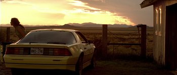 Movie still from “The Three Burials of Melquiades Estrada” (2005), directed by Tommy Lee Jones – A car parked in a field near a fence; Wide shot, Low angle