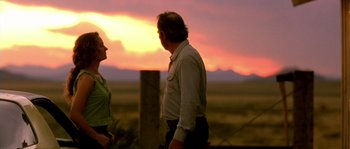 Movie still from “The Three Burials of Melquiades Estrada” (2005), directed by Tommy Lee Jones – A man and a woman standing next to each other in front of a sunset; Medium shot, Low angle
